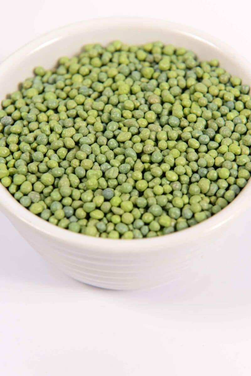 Green polymer-coated prills in a dish showing uniform granule size.