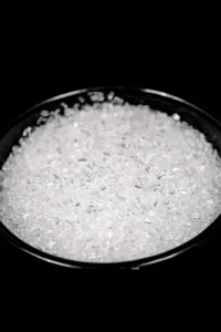 Black bowl of magnesium sulphate showing the white crystals.