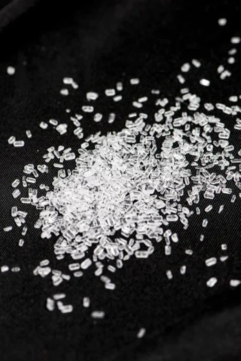 Close-up of white crystalline Magnesium Sulphate on a black surface