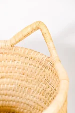 Handcrafted large rope-style basket with handles used as decorative indoor pot cover.