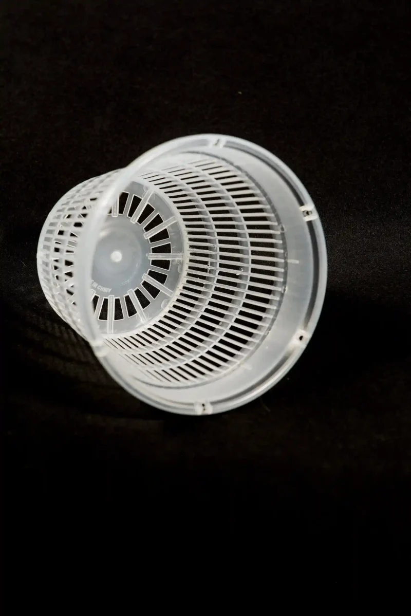 Close-up of transparent net pot with vertical airflow slots.